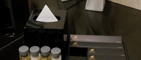 Un mostrador de baño de hotel con artículos de aseo, una caja de pañuelos y dos plantas en macetas.