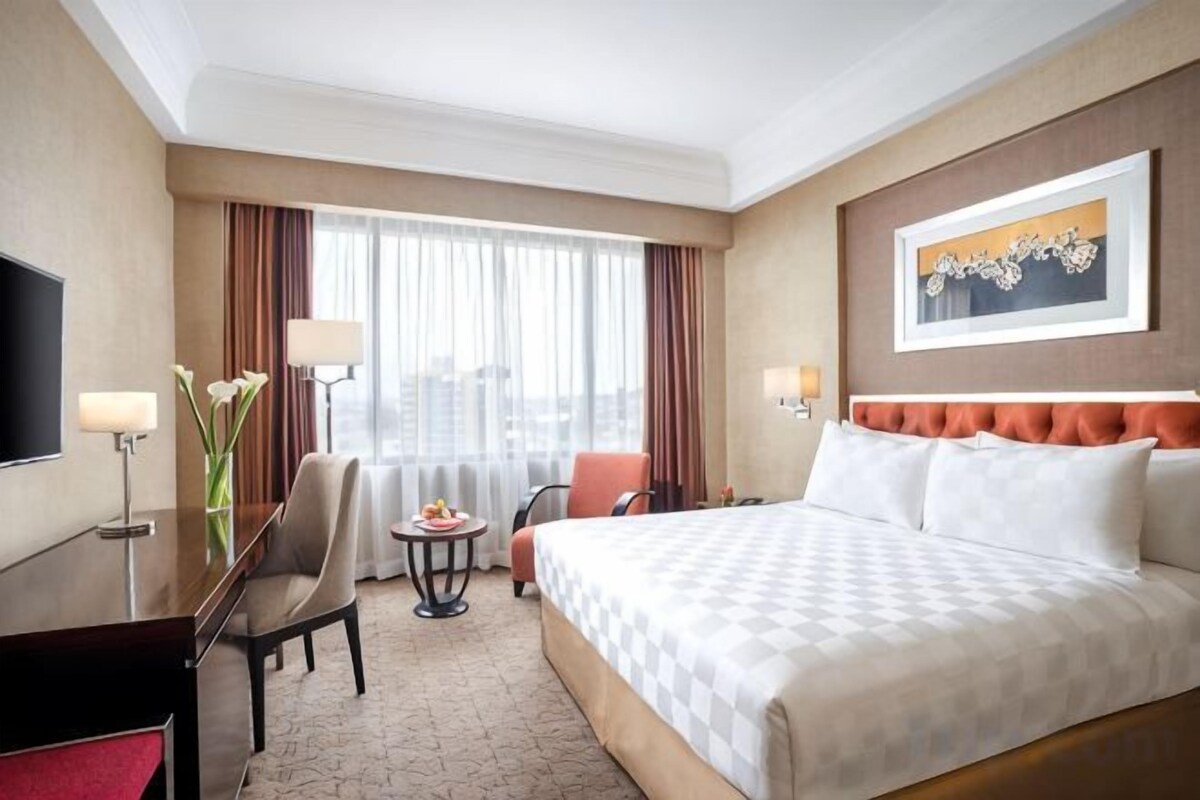 A hotel room with a bed, desk, chair, and a television.