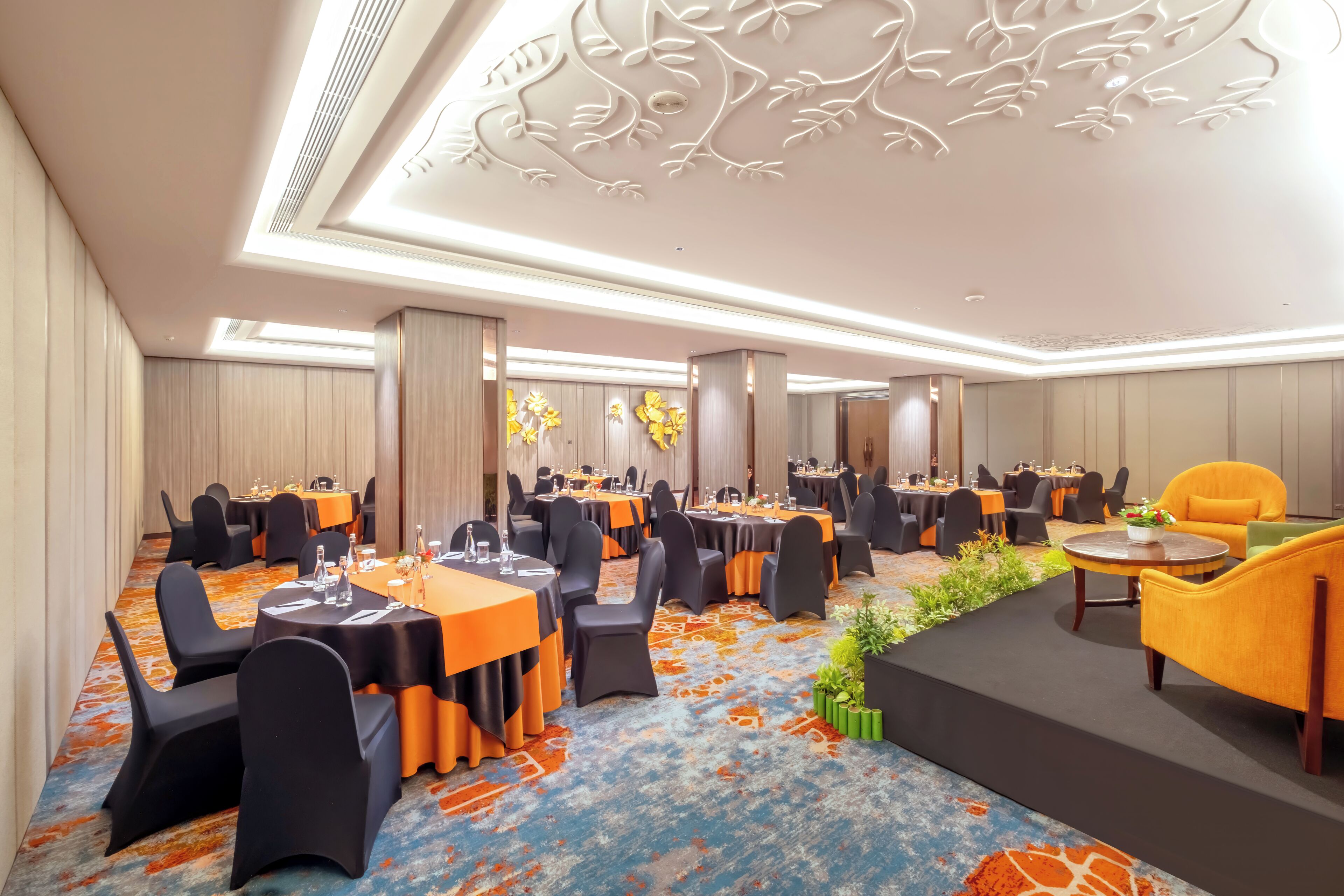Un salón de conferencias con mesas y sillas, un escenario y un techo decorativo.