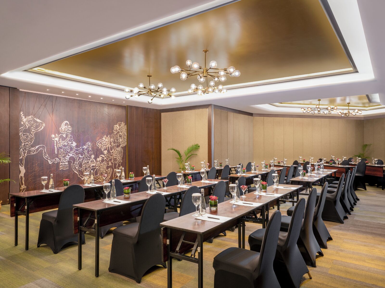 Un salón de conferencias con mesas largas, sillas y un techo con candelabros.