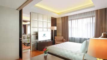 Una habitación de hotel con cama, escritorio, silla, televisor y ventana con cortinas.
