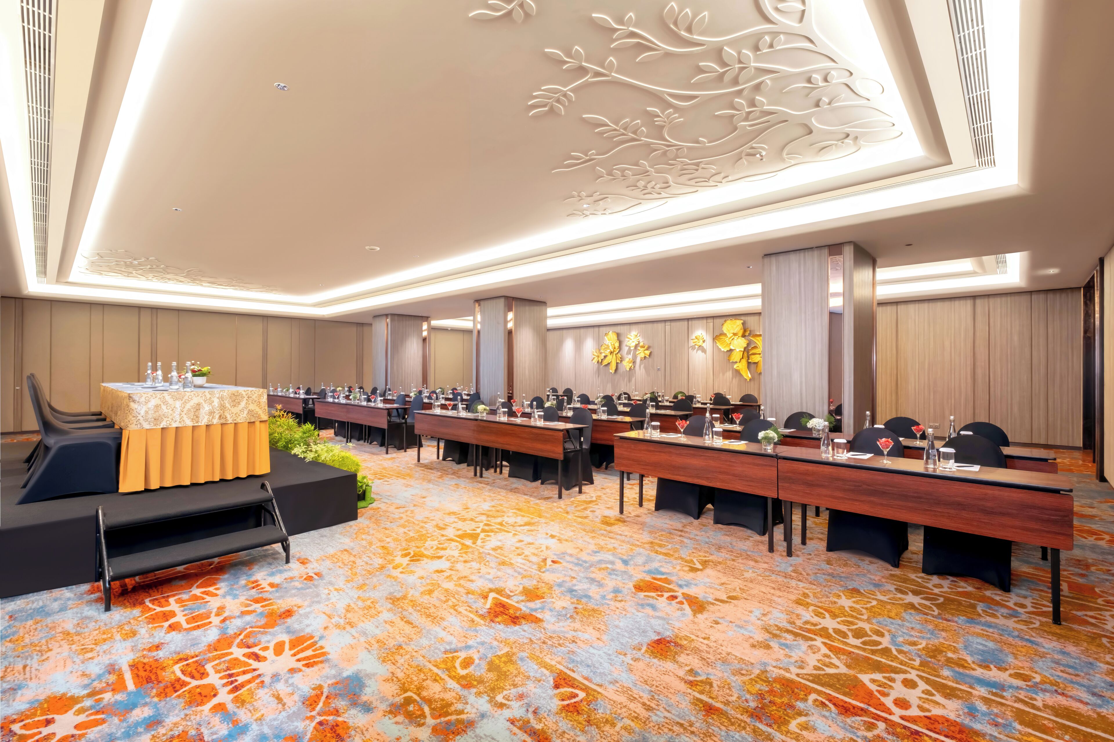 Un salón de conferencias con una larga mesa, sillas y un escenario con un atril.