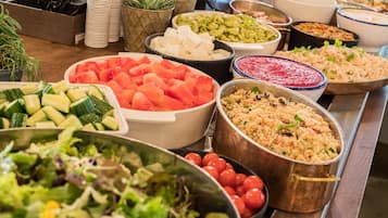 Een buffet met diverse gerechten, waaronder salades, fruit en rijst.