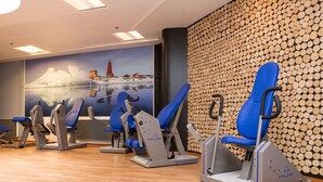 Una palestra con attrezzature per l'esercizio fisico e un murale raffigurante un faro.