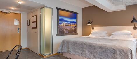 Habitación de hotel con cama, una silla, un escritorio, una ventana y una puerta.