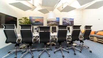 A conference room with six black office chairs, a white table, and a potted plant.