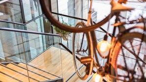 Un interno moderno con ringhiera in vetro, pavimento in legno e una bicicletta appesa a decorazione.