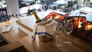 Ein Restaurantambiente mit einem Tisch für zwei Personen, einer Champagnerflasche und zwei Gläsern.