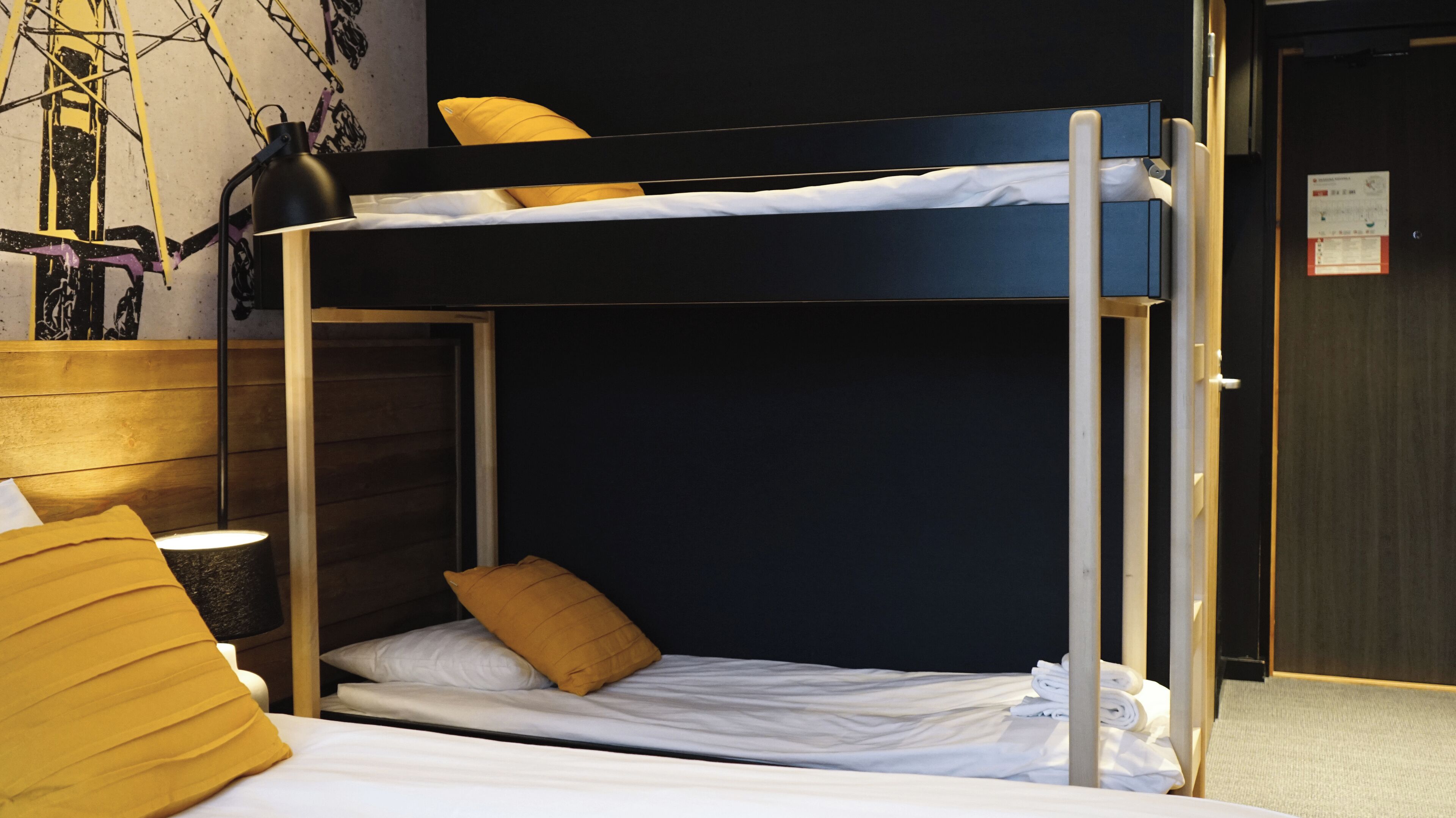 A bunk bed with a wooden frame, white bedding, and a yellow pillow.