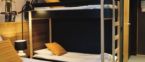 A bunk bed room with a wooden headboard, a bedside lamp, and a wall-mounted shelf with a lamp.