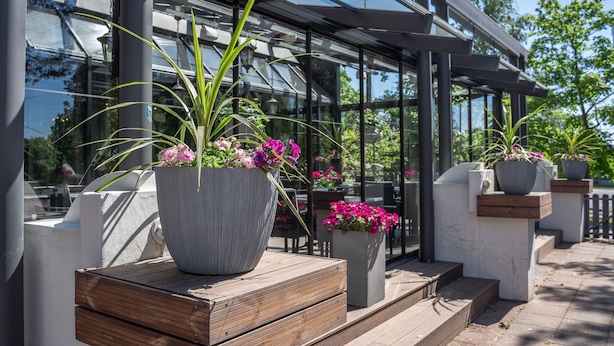 Um edifício moderno com grandes janelas de vidro, área de estar ao ar livre e plantas em vasos.