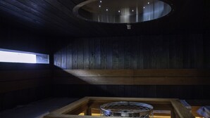 Interior de madeira com mesa de churrasqueira e claraboia.