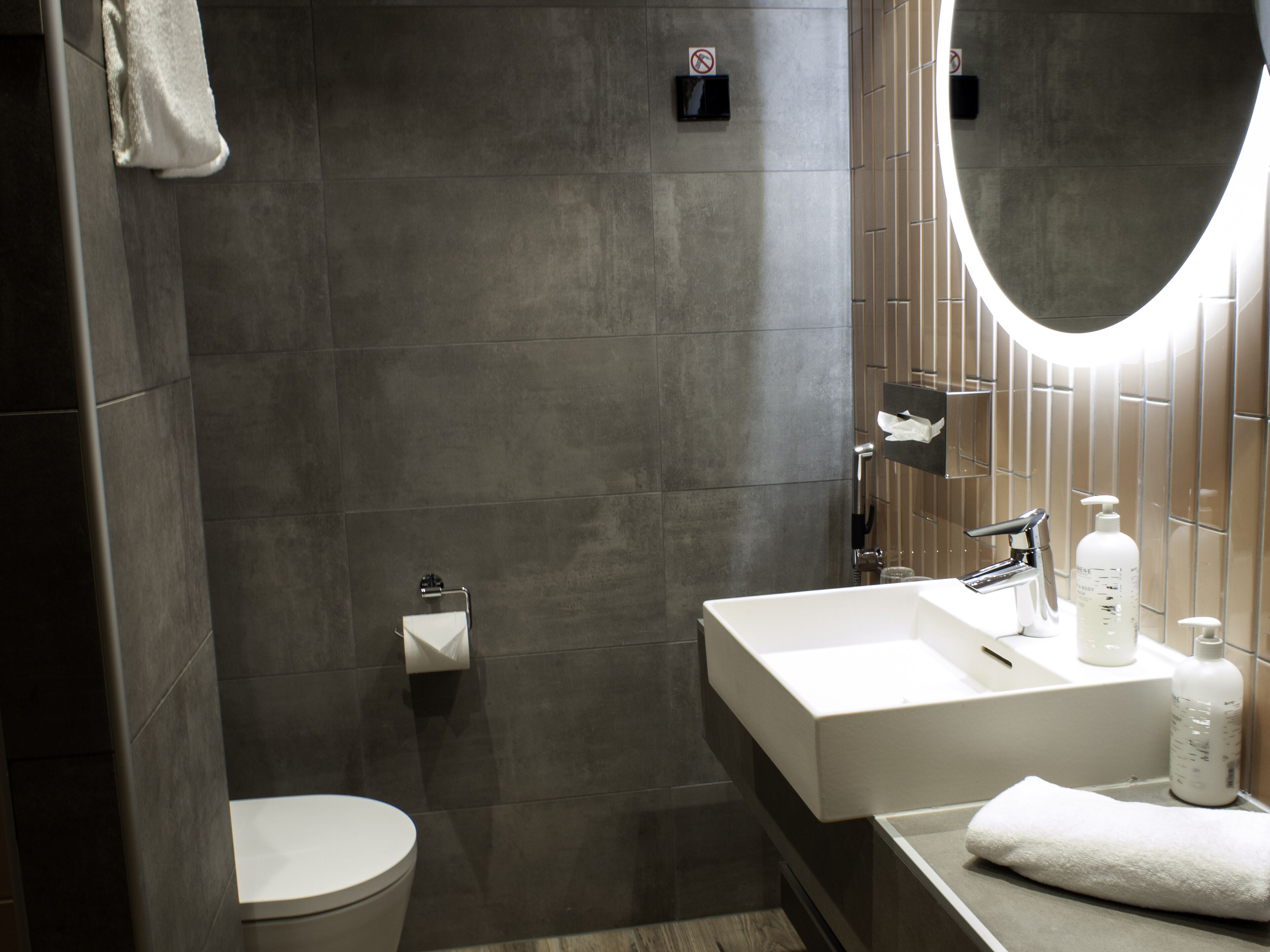 Une salle de bain moderne avec des toilettes, un lavabo et un miroir.