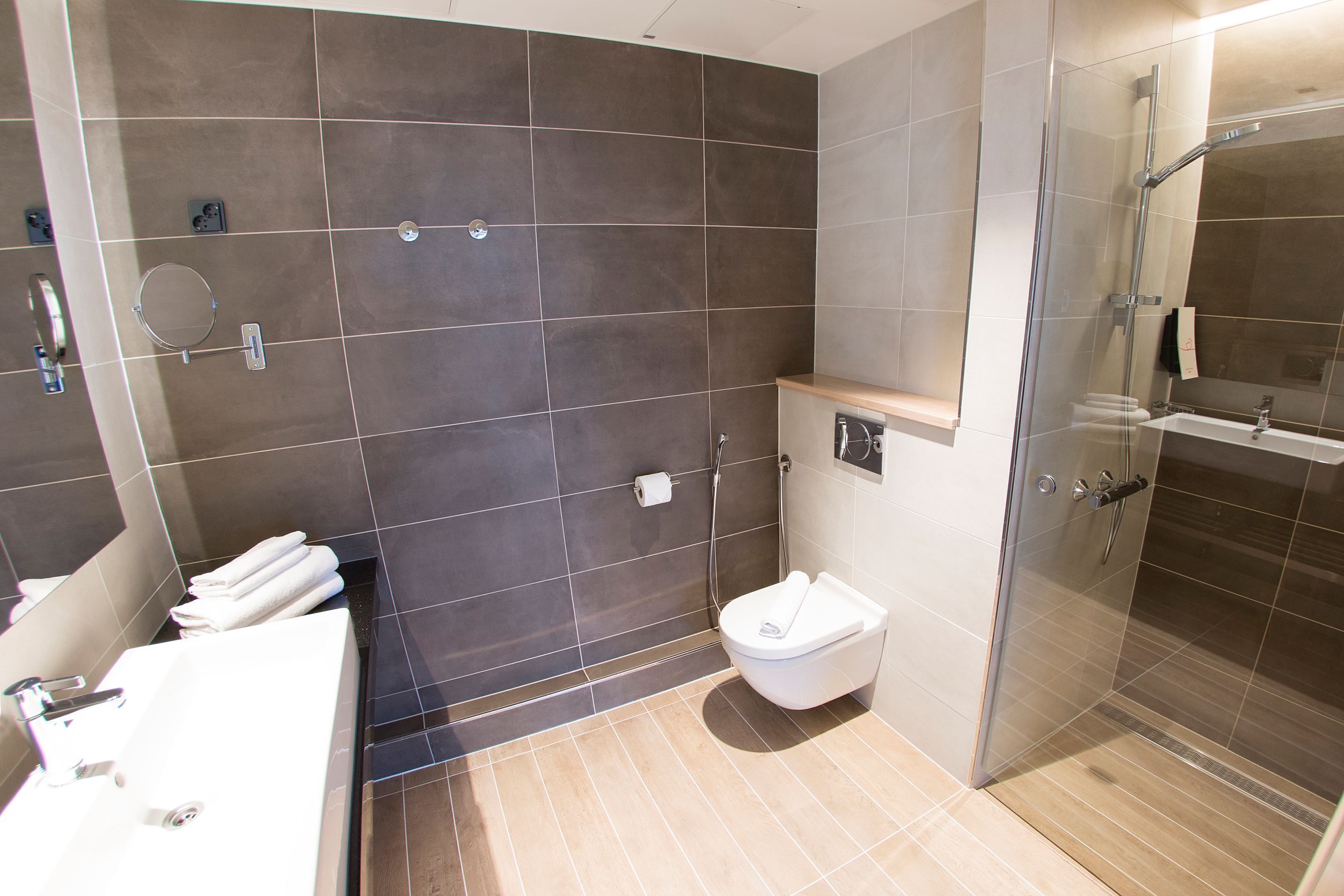 A modern bathroom with a glass-enclosed shower, a white toilet, and a sink with a mirror.