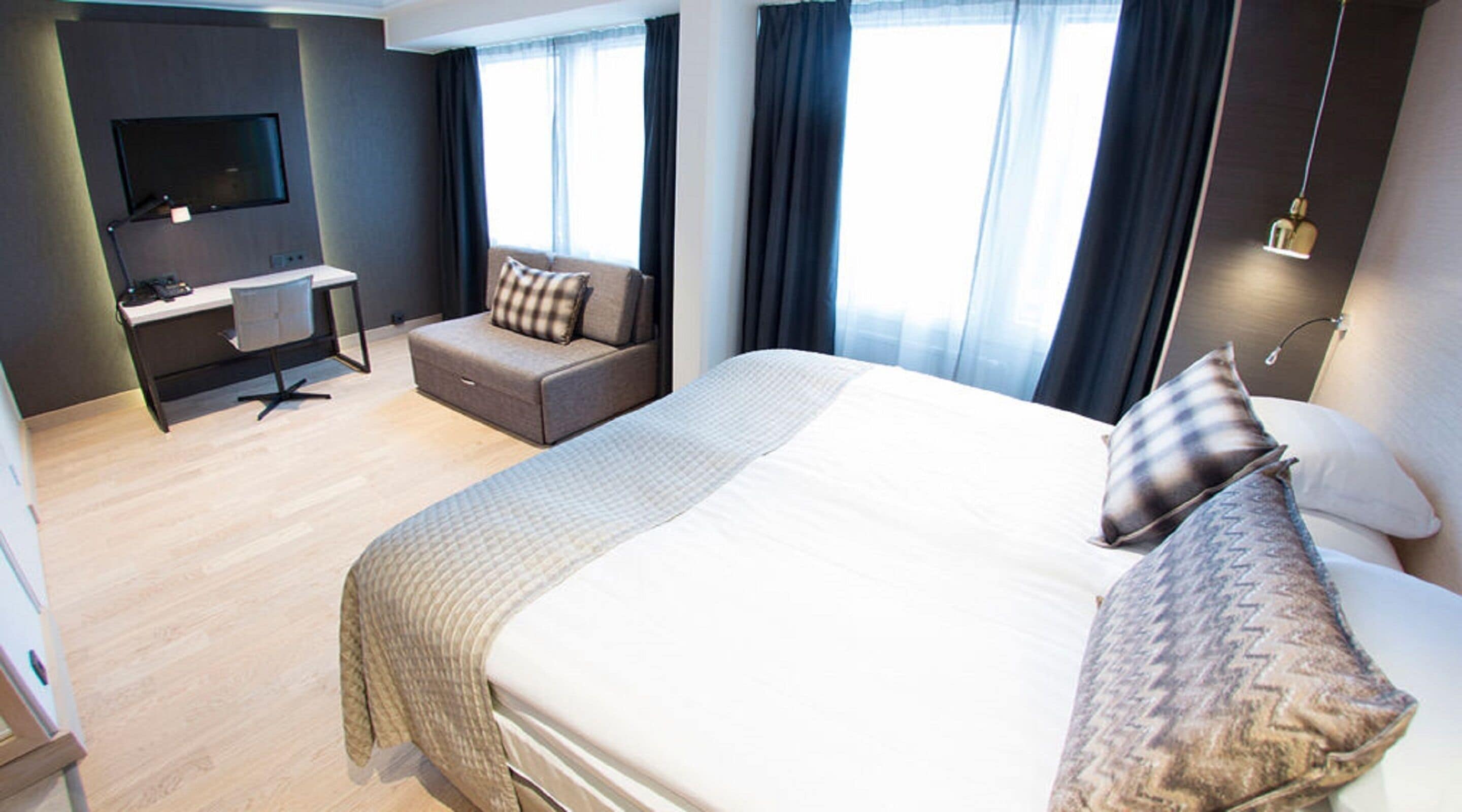 Une chambre d’hôtel avec un grand lit, un bureau avec une chaise, une télévision et un canapé.
