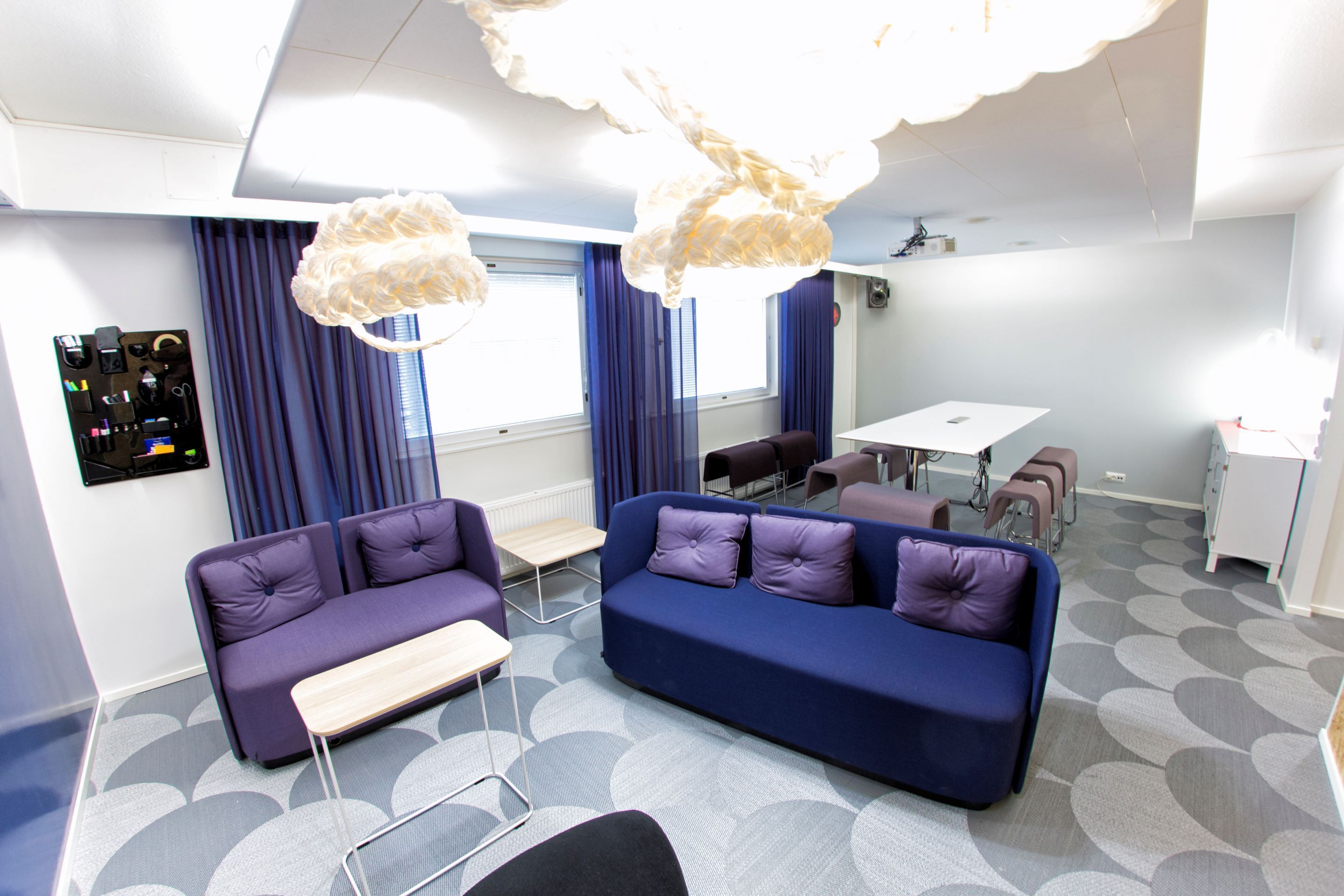 A modern office space with a blue sofa, a small table, and a dining area.