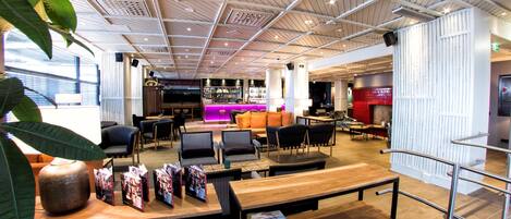 A modern lounge area with seating, a bar, and a reception desk.