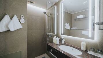 Un baño moderno con ducha de vidrio, encimera de granito y un espejo grande.