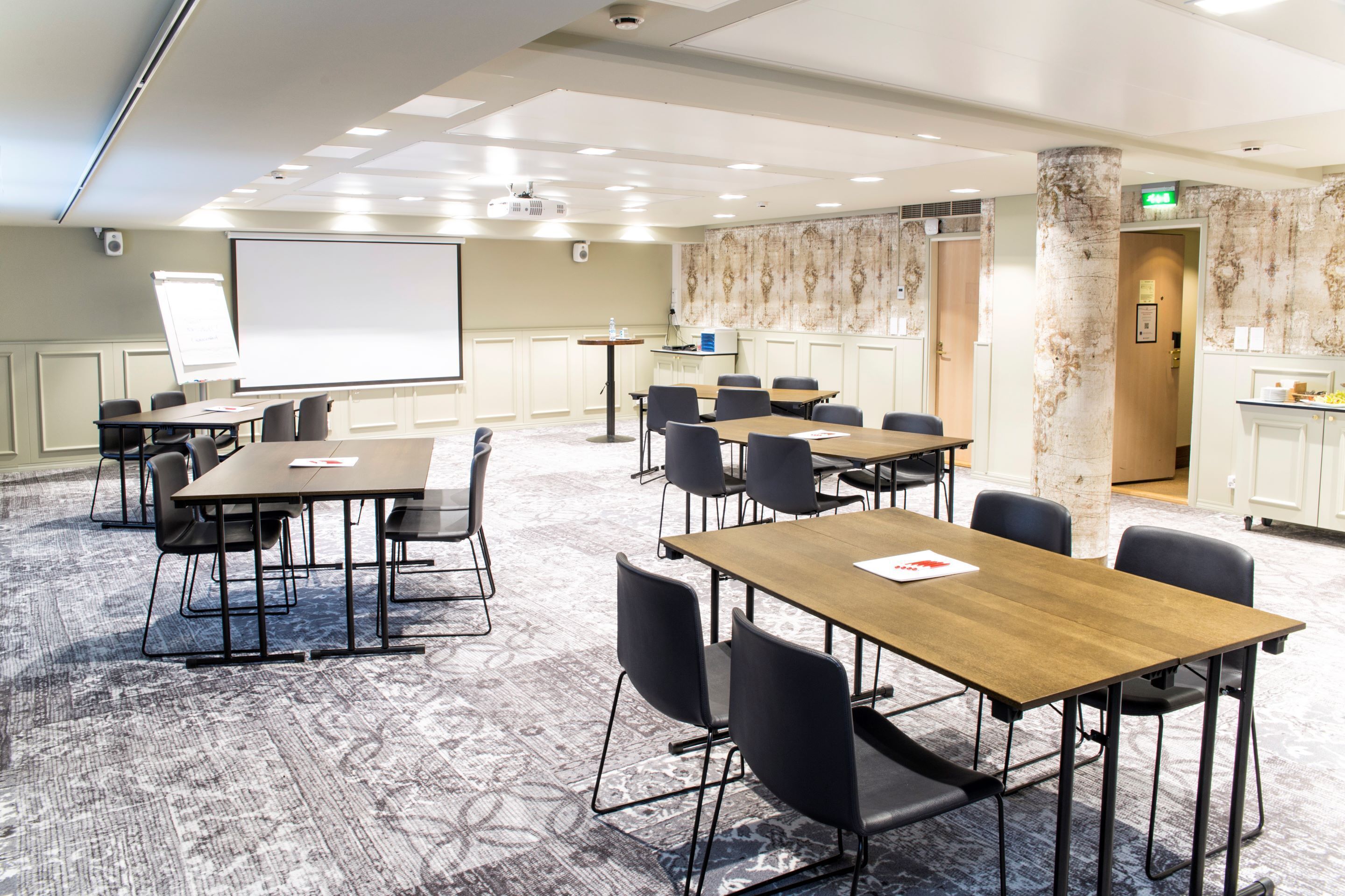 A conference room with multiple tables and chairs, a projector screen, and a whiteboard.