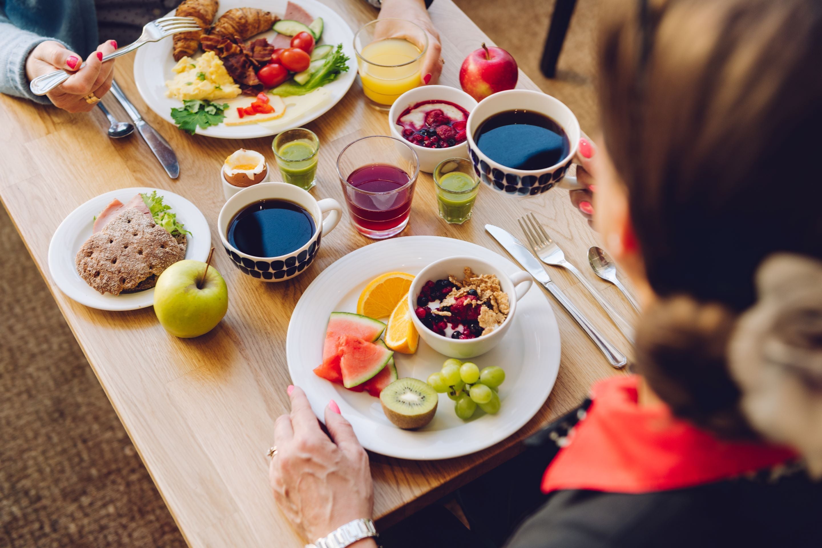 Een ontbijttafel met diverse soorten eten, zoals fruit, een croissant en een kom ontbijtgranen.