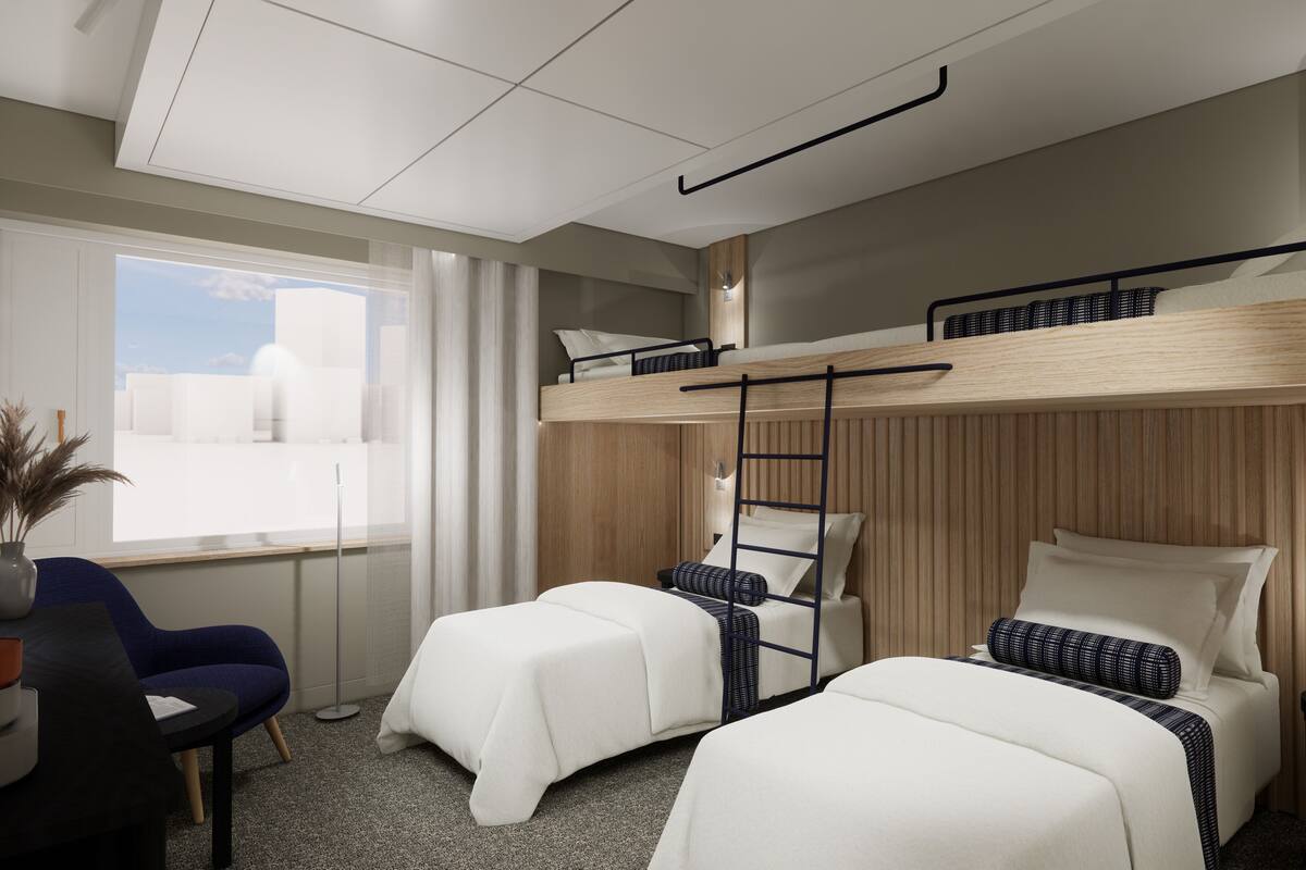 A hotel room with bunk beds, a desk, a chair, a vase with dried plants, and a window with a view of buildings.