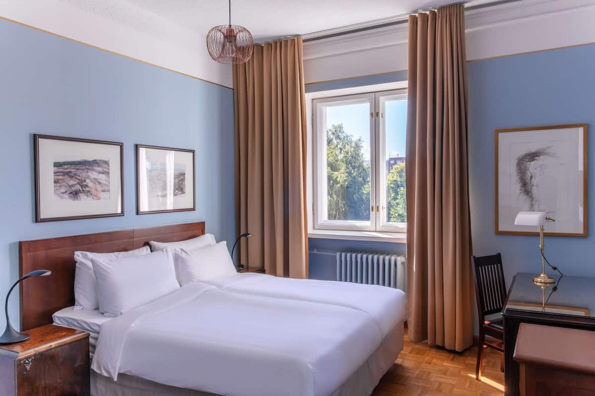 Una habitación de hotel con una cama grande, un escritorio y una ventana con cortinas.
