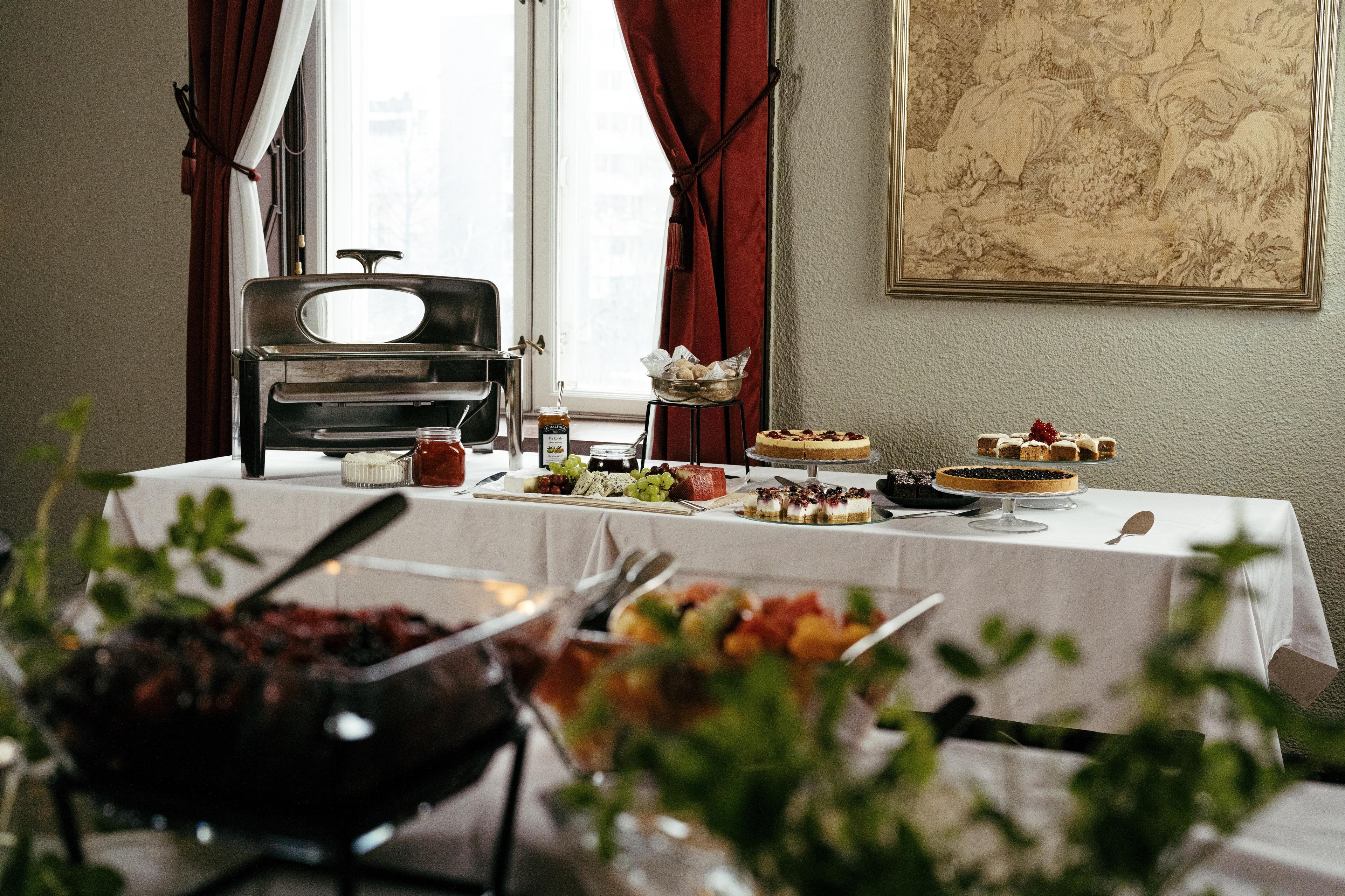 A buffet table with various food items, a vintage radio, and a window with curtains.