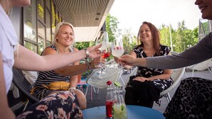A group of people toasting with wine glasses at an outdoor table with chairs and a wicker table. - Original Sokos Hotel Lappee (Lappeenranta)