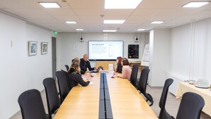 A conference room with a long table, black chairs, and a projector screen displaying a presentation. - Original Sokos Hotel Lappee (Lappeenranta)