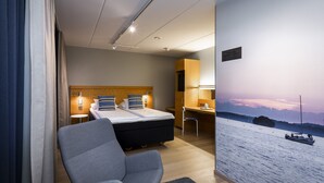 A hotel room with a bed, a desk, a chair, and a large window with a view of a body of water and boats. - Original Sokos Hotel Lappee (Lappeenranta)