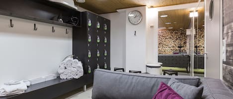 Un baño moderno con un sofá gris, techo de madera, un reloj y un toallero de pared.