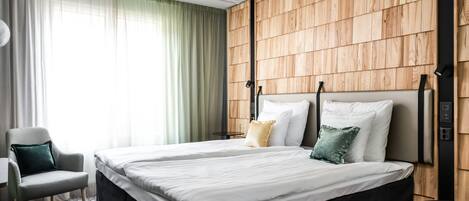 Una habitación de hotel moderna con una cama grande, una silla y un panel de pared de madera.
