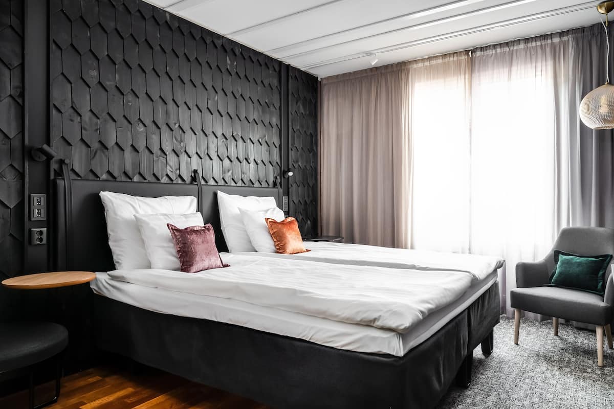 Une chambre d’hôtel moderne avec un grand lit, une petite table, une chaise et un mur au revêtement original.