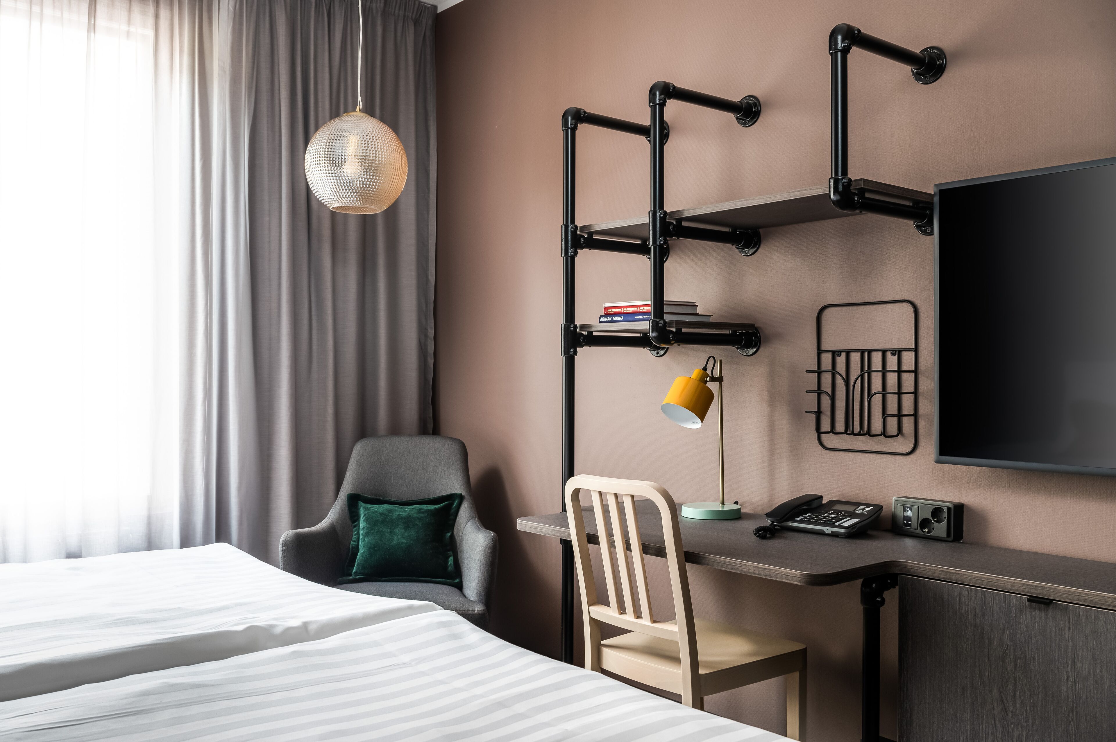 Una habitación de hotel con una cama, un escritorio con silla, un televisor y una lámpara.