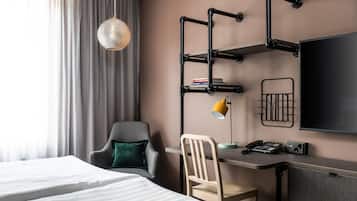 Una habitación de hotel con una cama, un escritorio con silla, un televisor y una lámpara.