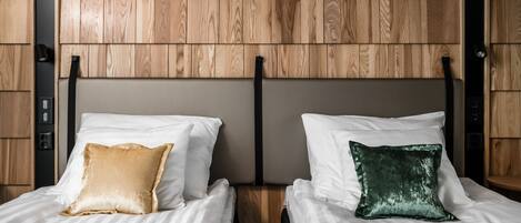 A hotel room with two beds, each with a pillow and a headboard.