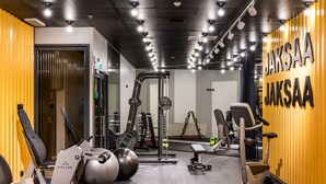 Ett gym med träningsutrustning, en viktbänk och en vägg med texten ”JAKSAA JAKSAA”.