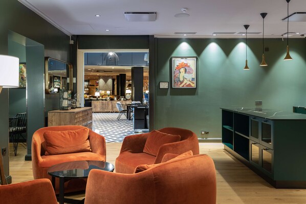 A modern hotel lobby with orange seating, a bar area, and a view into the dining space. - Scandic Hamburger Börs (Turku)