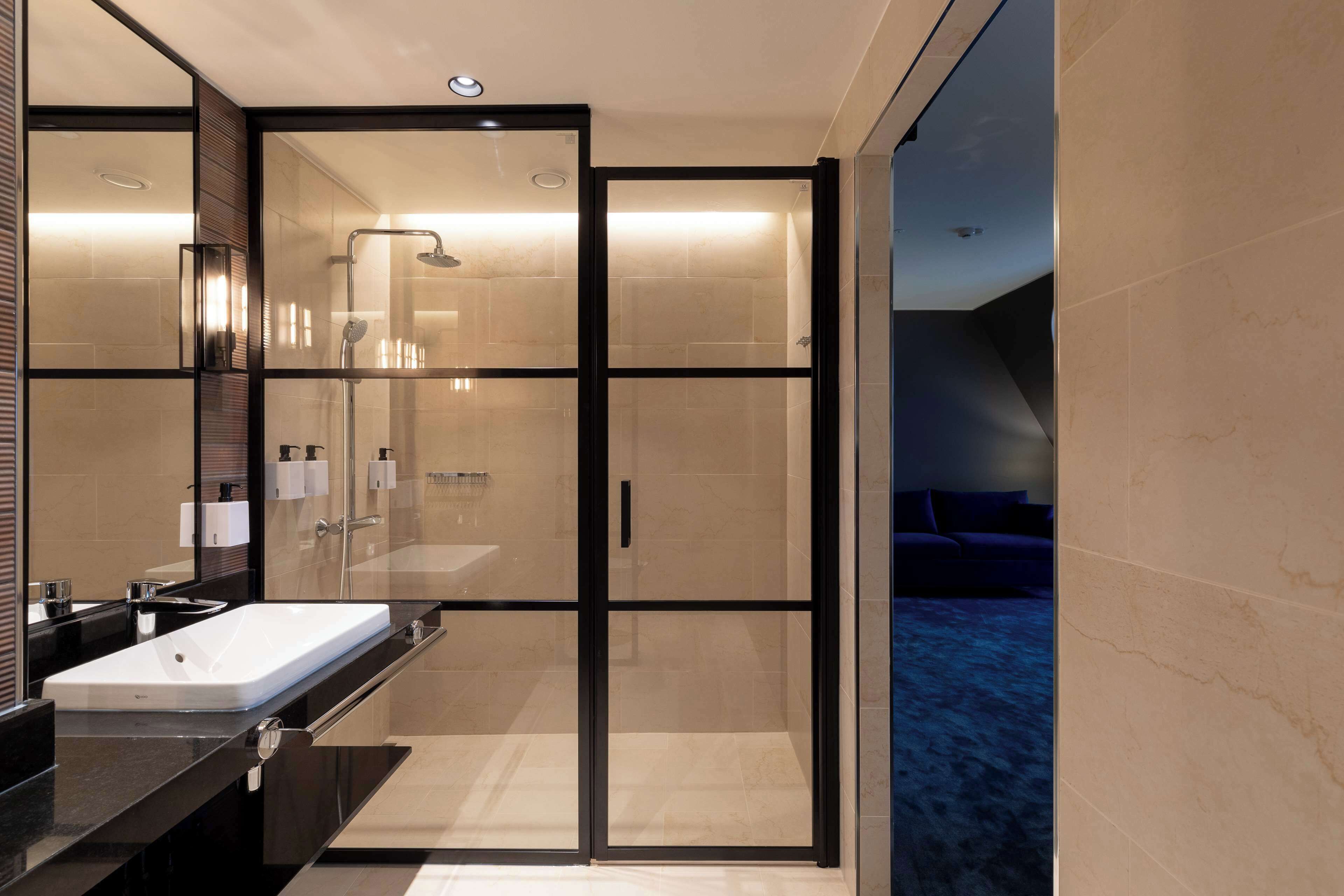 Une salle de bain moderne dotée d’une douche à parois de verre, d’un grand lavabo et d’un miroir.