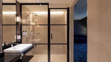 Ein modernes Badezimmer mit einer gläsernen Dusche, einem großen Waschbecken und einem Spiegel.