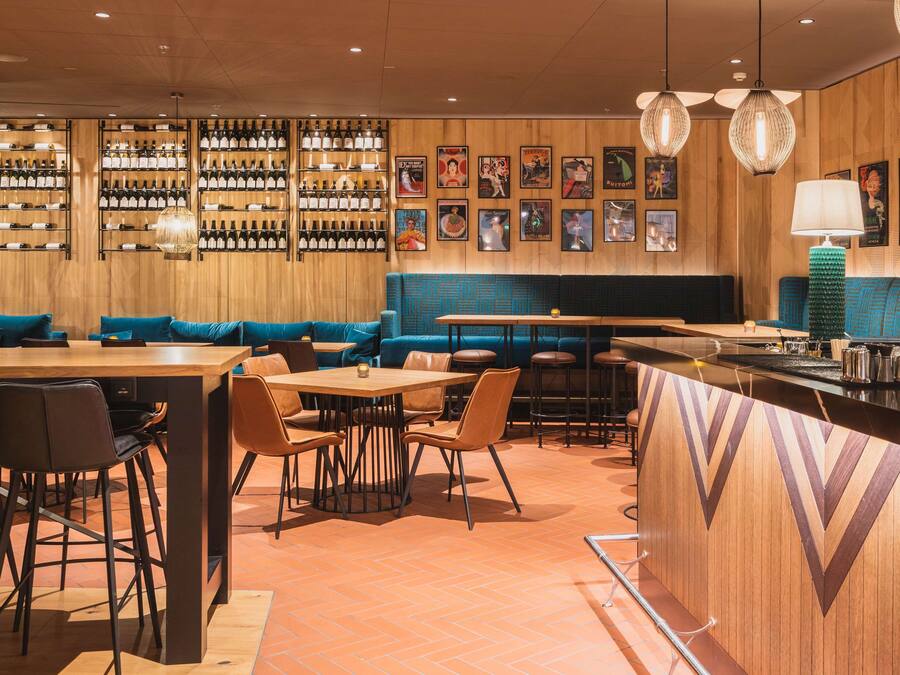 Un restaurant aux murs en bois, avec des sièges bleus et un espace bar.