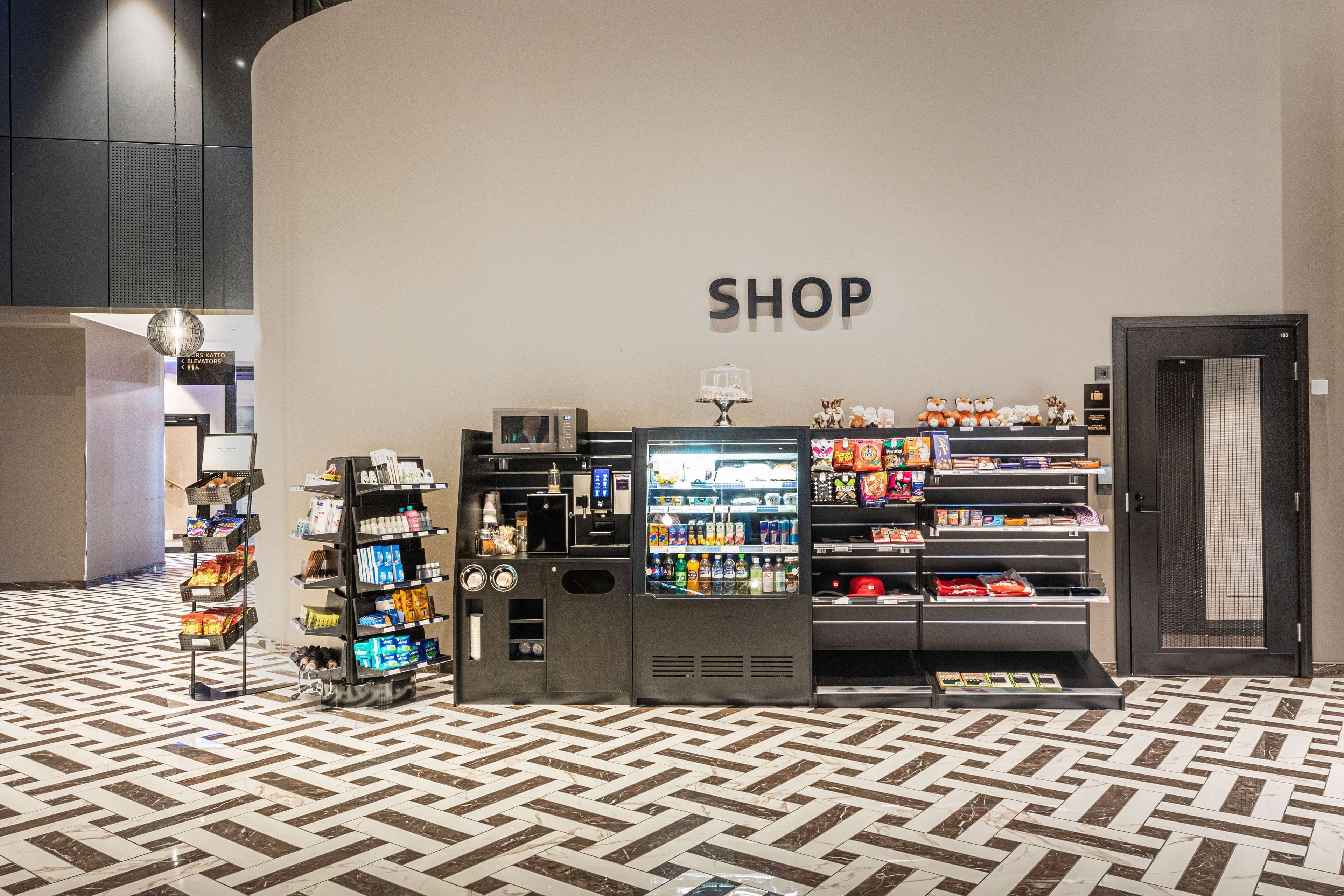 Een winkelgedeelte met schappen vol diverse producten, een automaat en een vitrine.