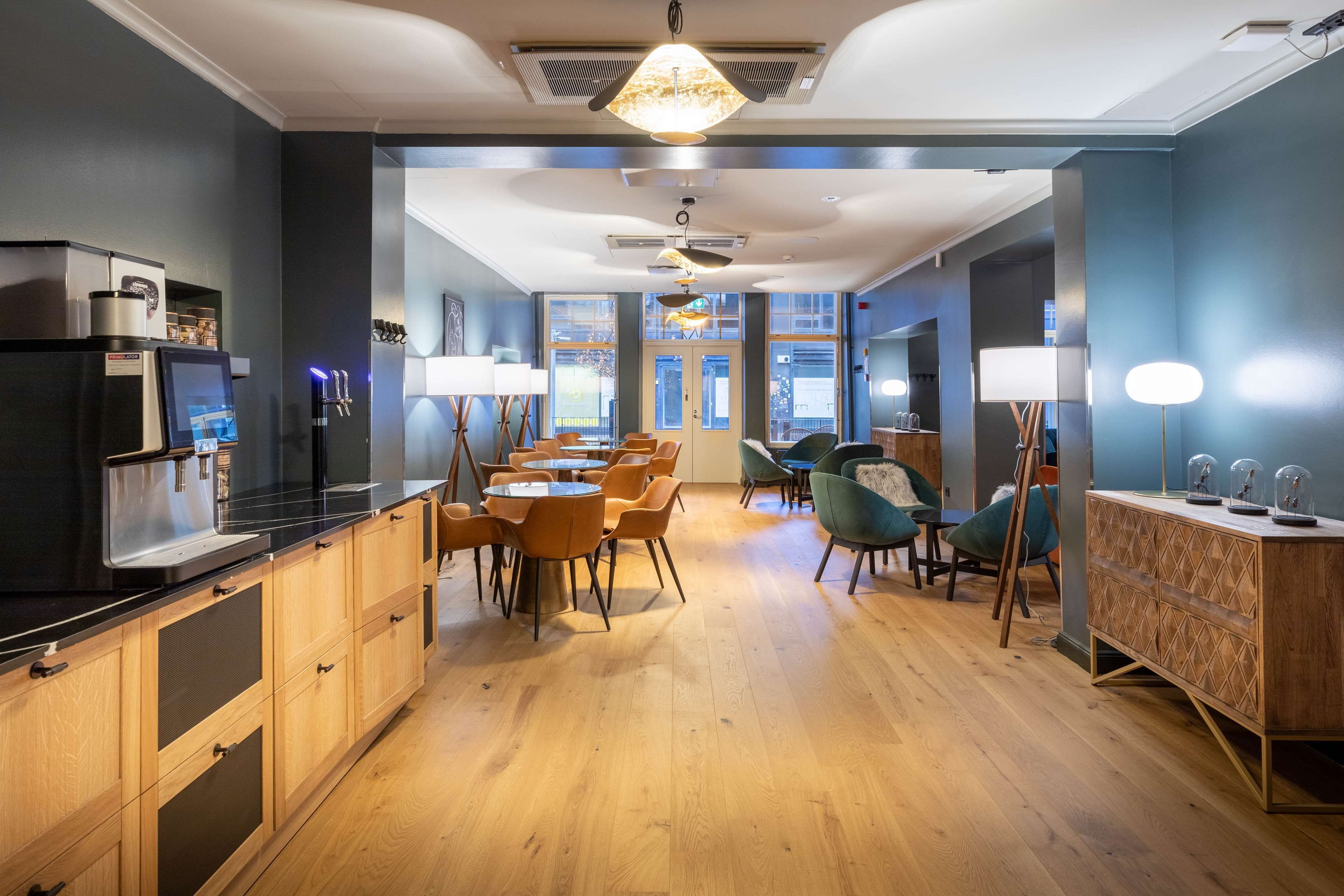Une cuisine moderne avec des meubles en bois, un plan de travail noir et un coin repas doté de chaises orange.