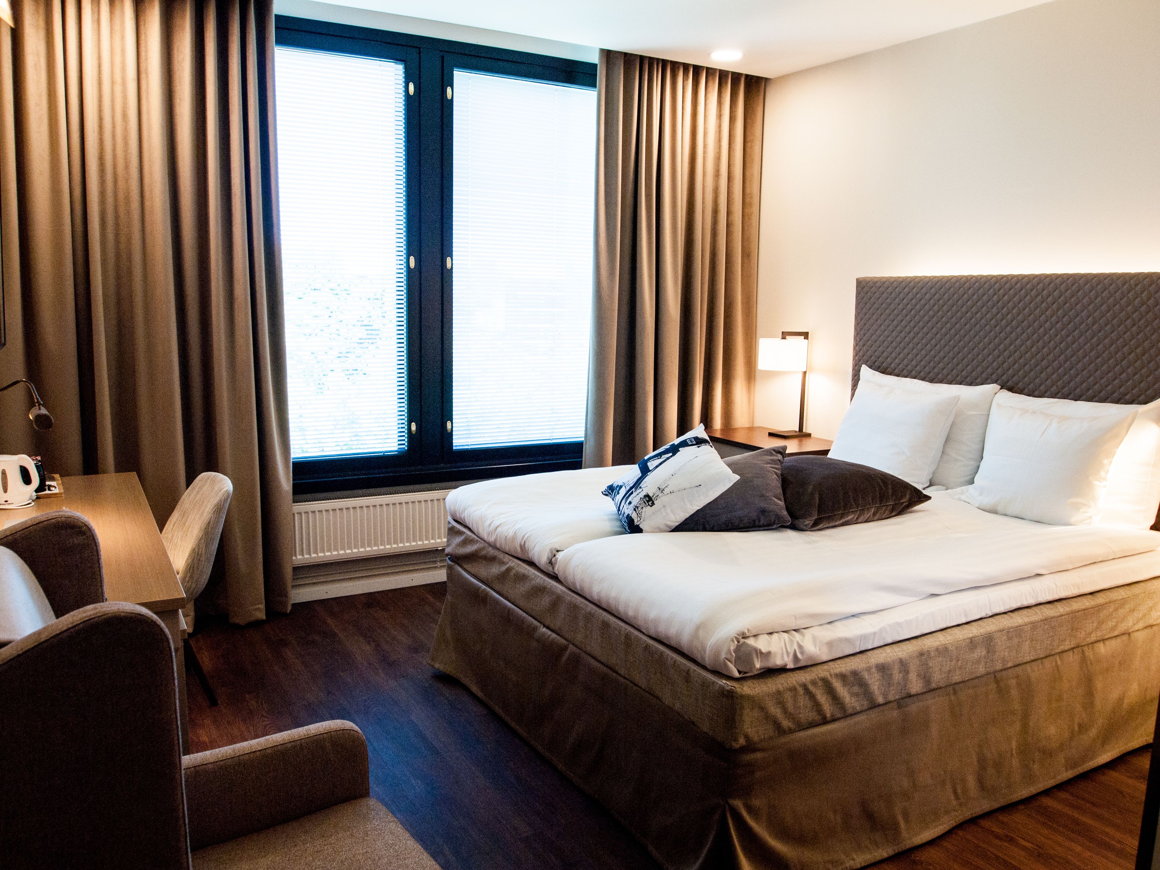 A hotel room with a bed, a desk, and a chair.