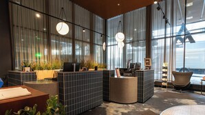 Una moderna zona de recepción con mostrador de baldosas, asientos y ventanas amplias.
