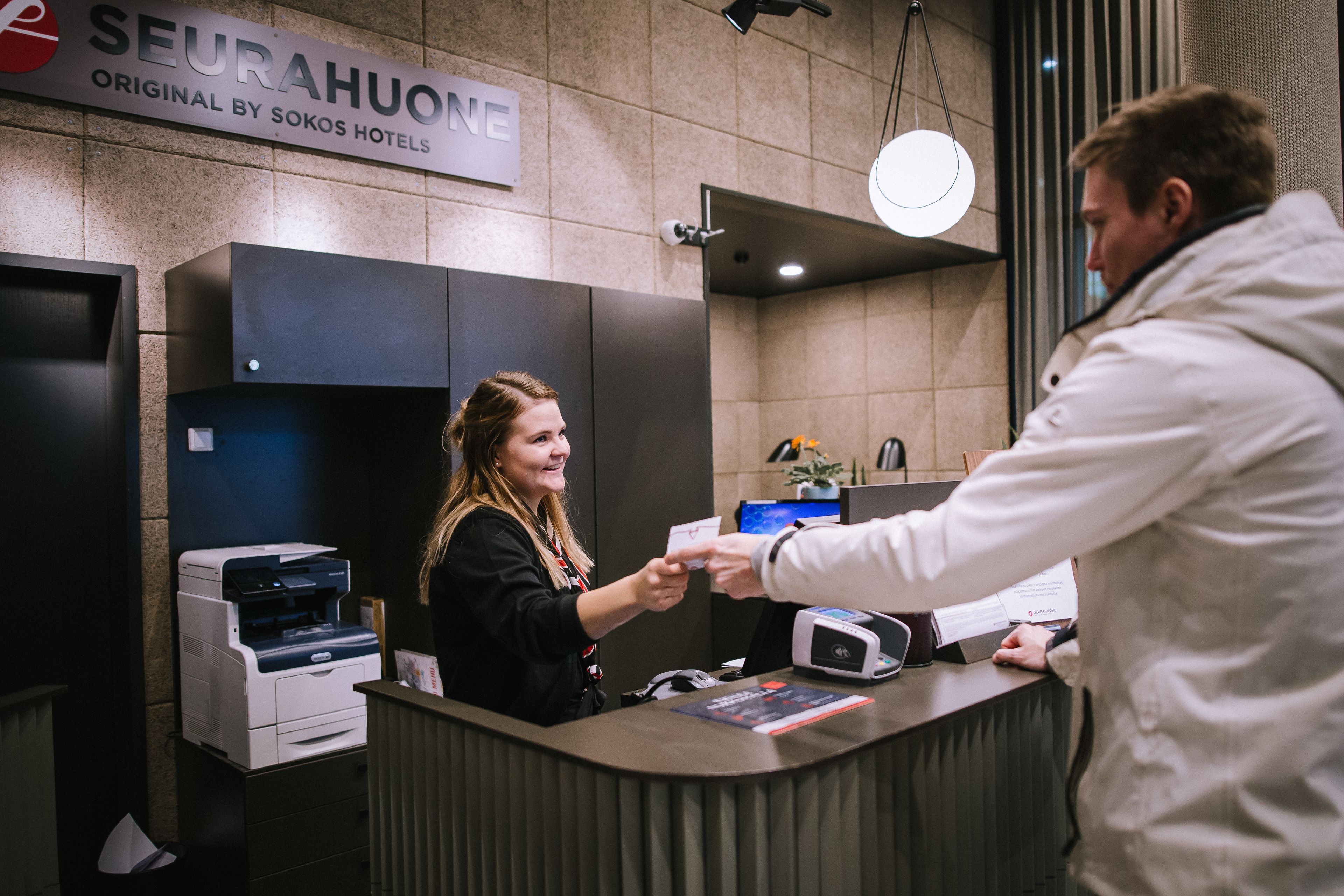 A reception desk with a sign reading "SEURAHUONE ORIGINAL BY SOKOS HOTELS".