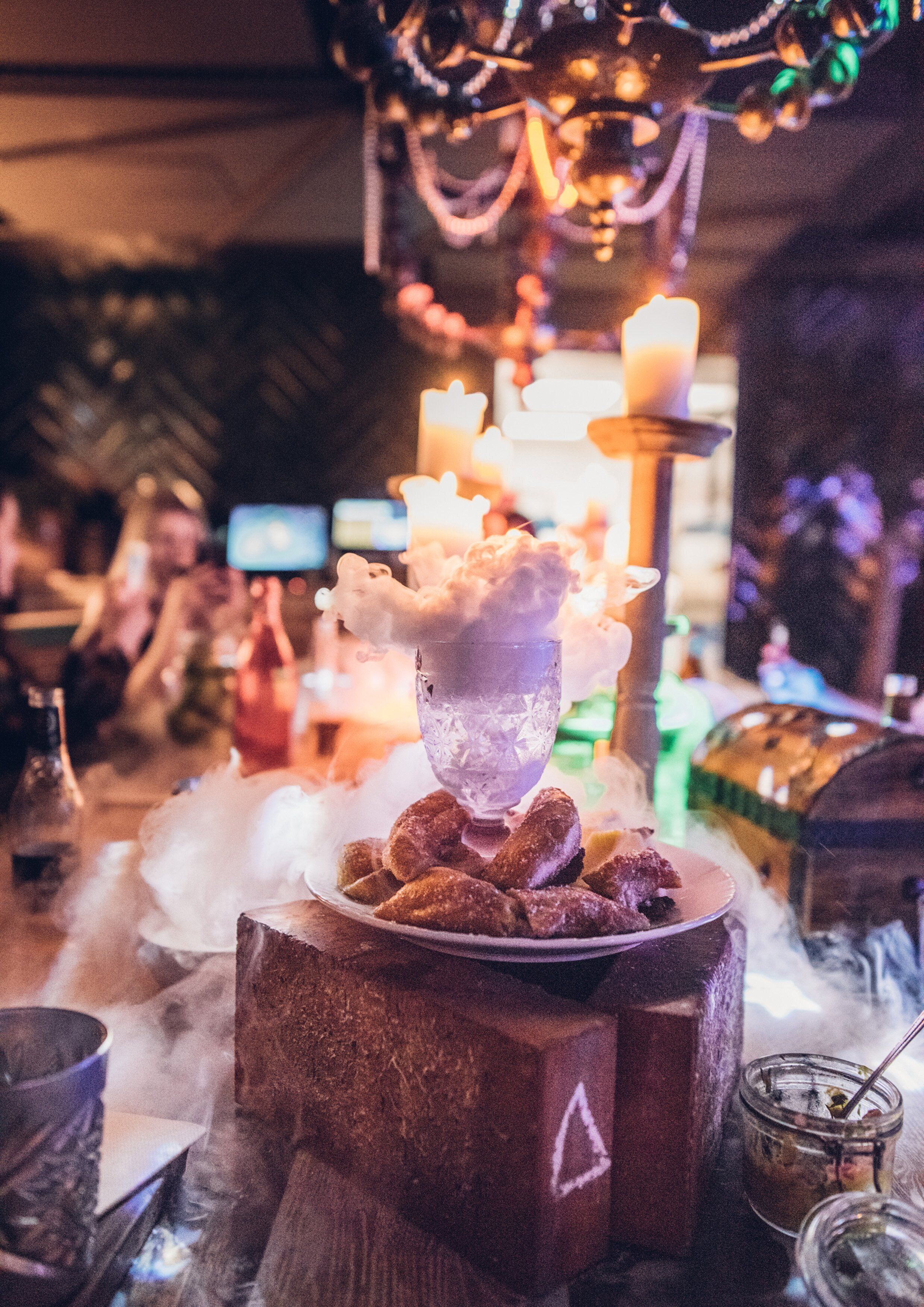 A bar area with a central ice sculpture, candles, and a wooden table.