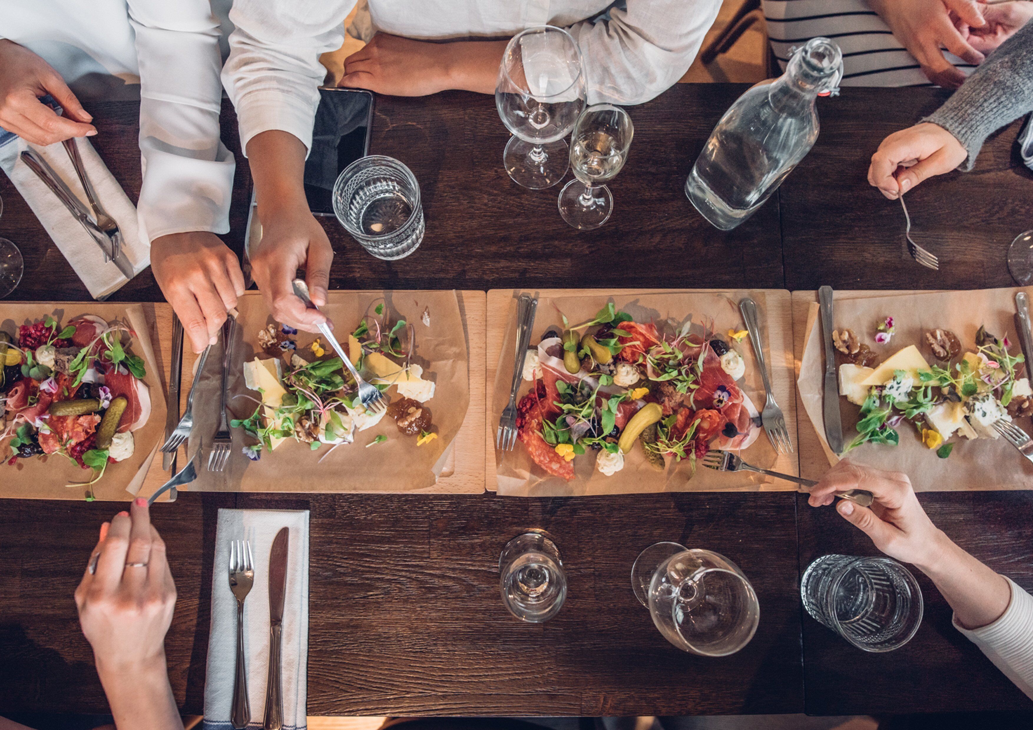 A dining table with multiple plates of food, utensils, and glasses.
