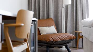 A modern room with a brown leather chair, a white floor lamp, and a grey curtain backdrop.