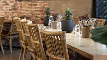 A wooden dining table with wicker chairs, potted plants, and a set of cutlery on the table.